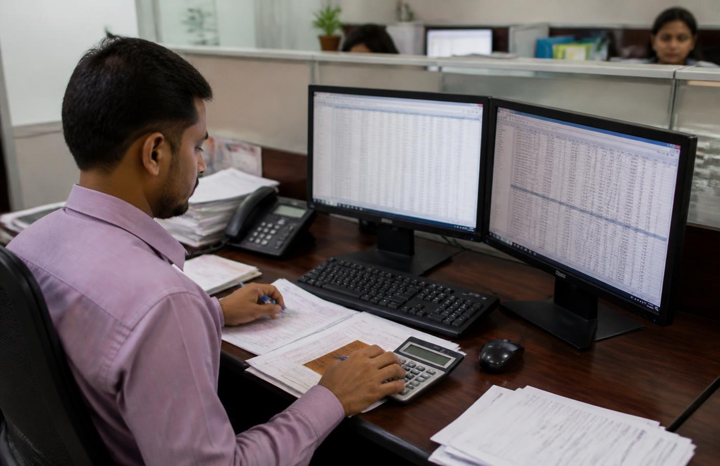 Indian hospital billing staff reconciling medical claims on computer at a hospital finance desk